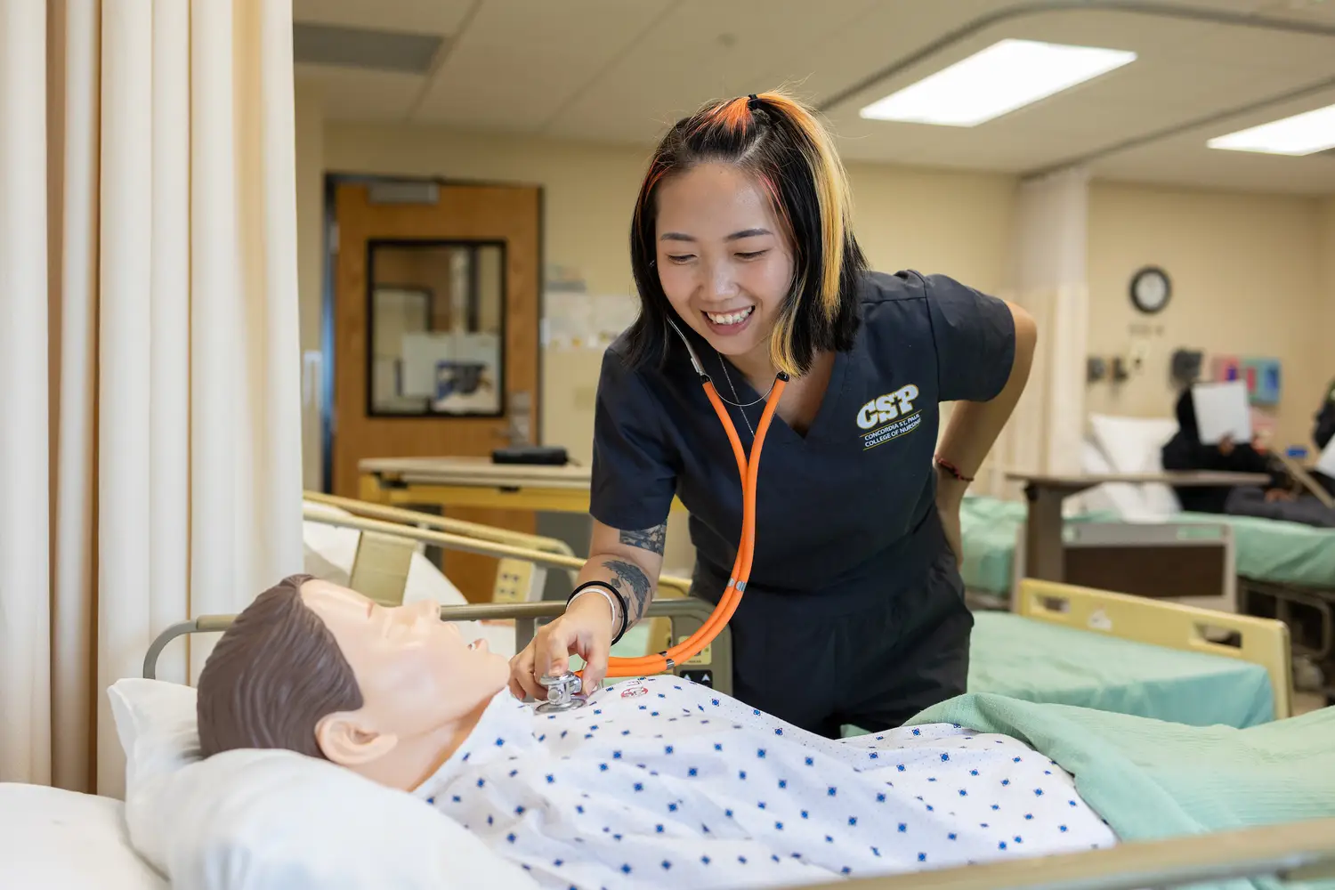 Two nursing students practicing using a medical device in a classroom setting.